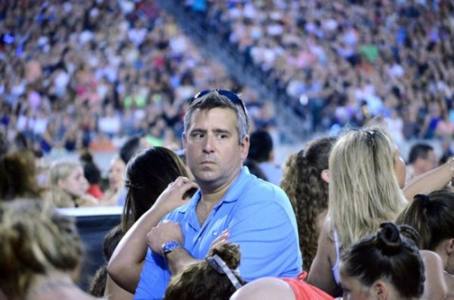 Dad suffering in a concert his daughter likes.