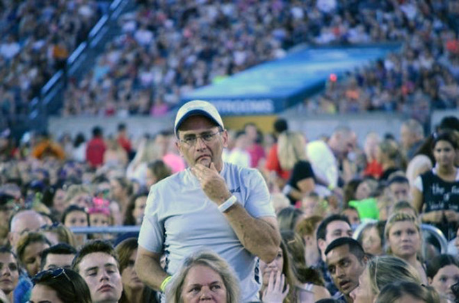 Dad suffering in a concert his daughter likes.