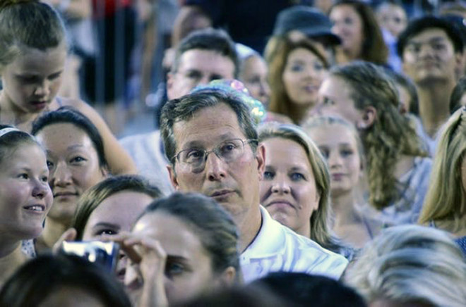 Dad suffering in a concert his daughter likes.